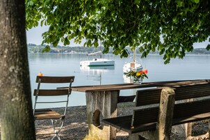A wooden bench and table by a lake with boats in the background.