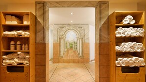 Een hotel lobby met een centrale marmeren pad, houten planken met handdoeken en toiletartikelen, en een klassieke boogpoort die uitkomt op een verre vergezichten.