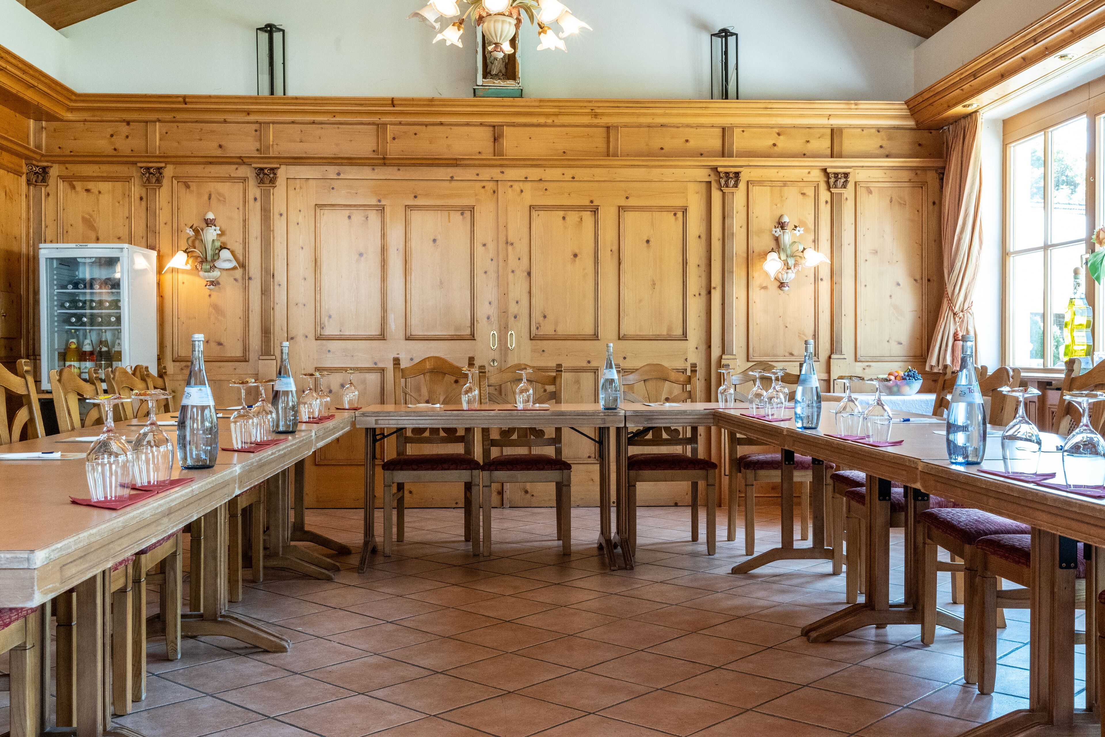A wooden dining area with a long table set for a meal, surrounded by chairs.
