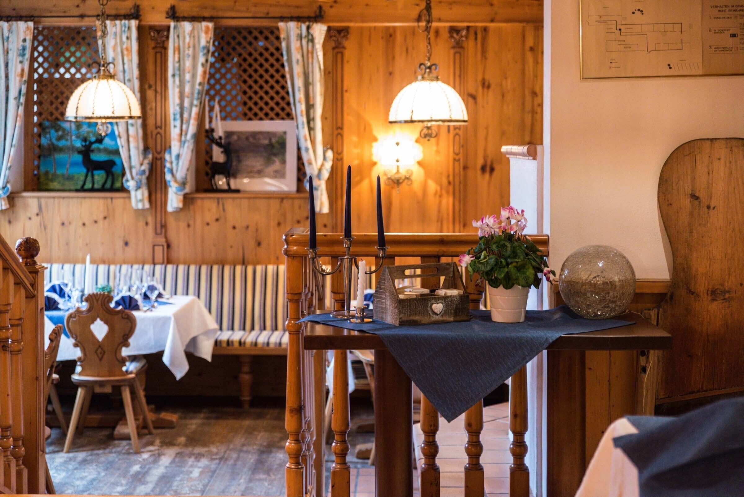 A wooden interior with a table set for dining, a bench, and a decorative wall with a map.
