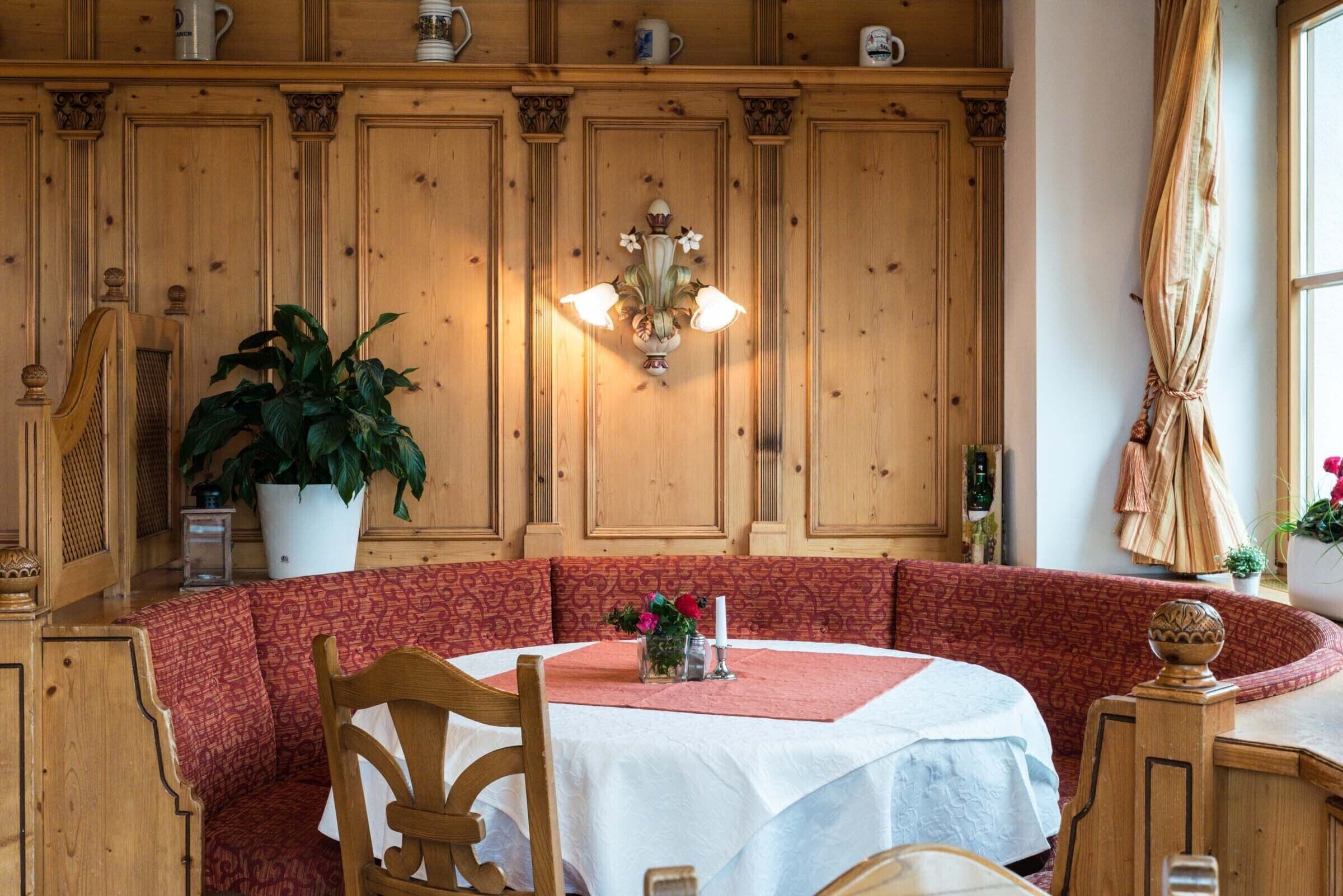 Un comedor acogedor con una mesa redonda, bancos de madera y una planta en maceta.