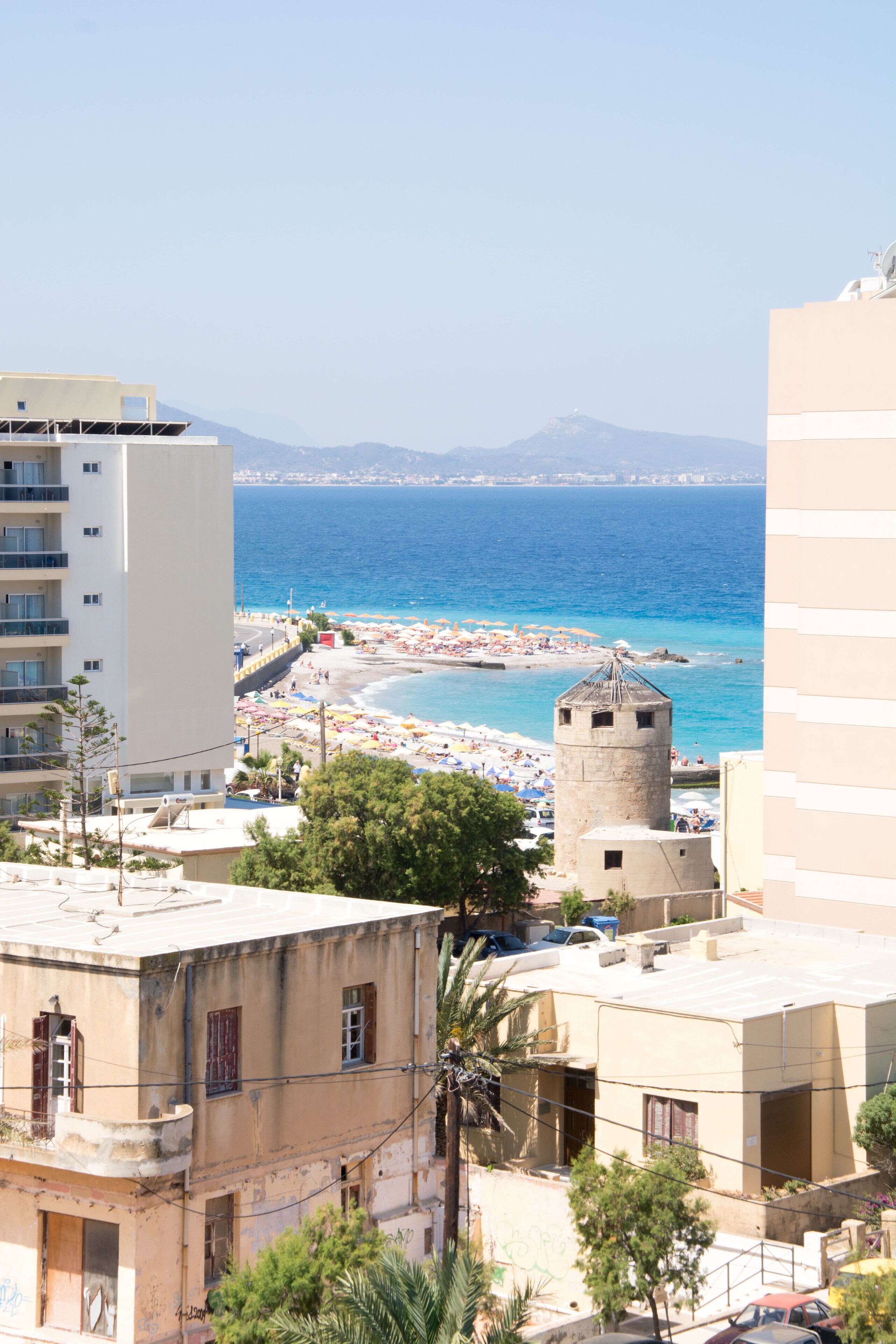 Un paisaje urbano costero con playa, una torre y edificios.