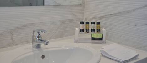 A bathroom sink with a mirror, a faucet, and a bottle holder with toiletries.