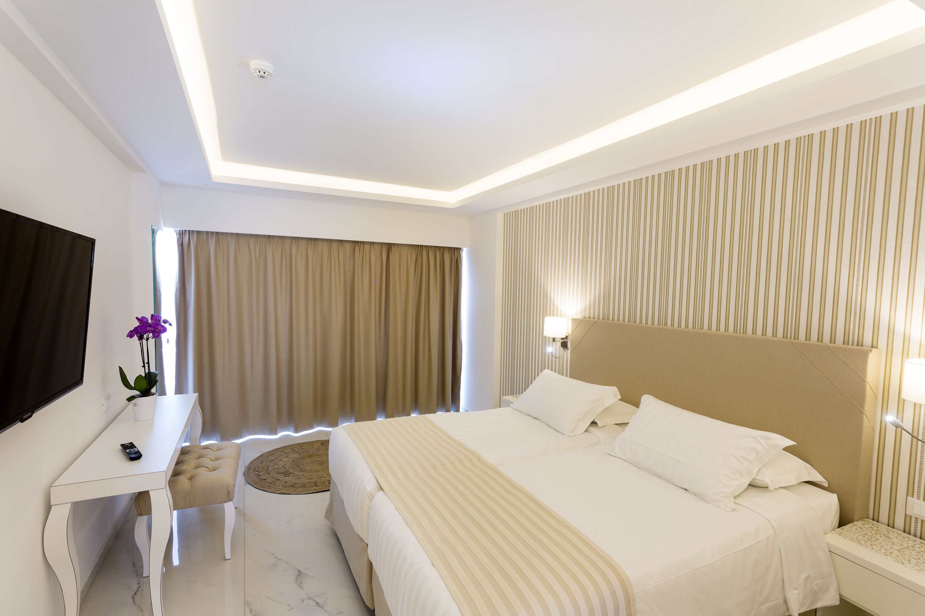 A modern hotel room with a large bed, a desk, and a television.