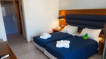 A hotel room with two beds, a desk, a telephone, and a small cabinet.