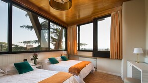 A room with two beds, large windows, and a view of trees. - Grand Hotel Panoramic (Montecatini Terme)