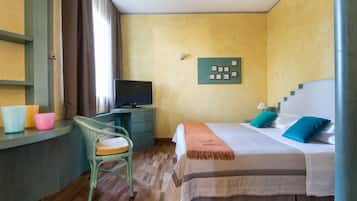 Una habitación de hotel con una cama, un escritorio con una computadora, una silla y un televisor.