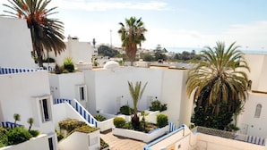 A courtyard with a checkered floor, palm trees, and a building with "HOTEL" written on the ground. - Tagadirt Appart-Hotel (Agadir)