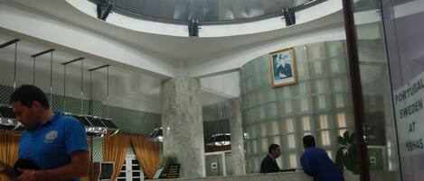 A lobby with a circular ceiling, marble columns, and a reception desk.