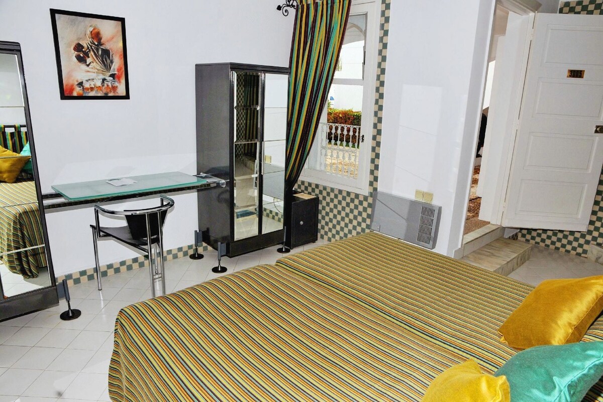A hotel room with a bed, a desk, a chair, a wardrobe, and a bathroom door.