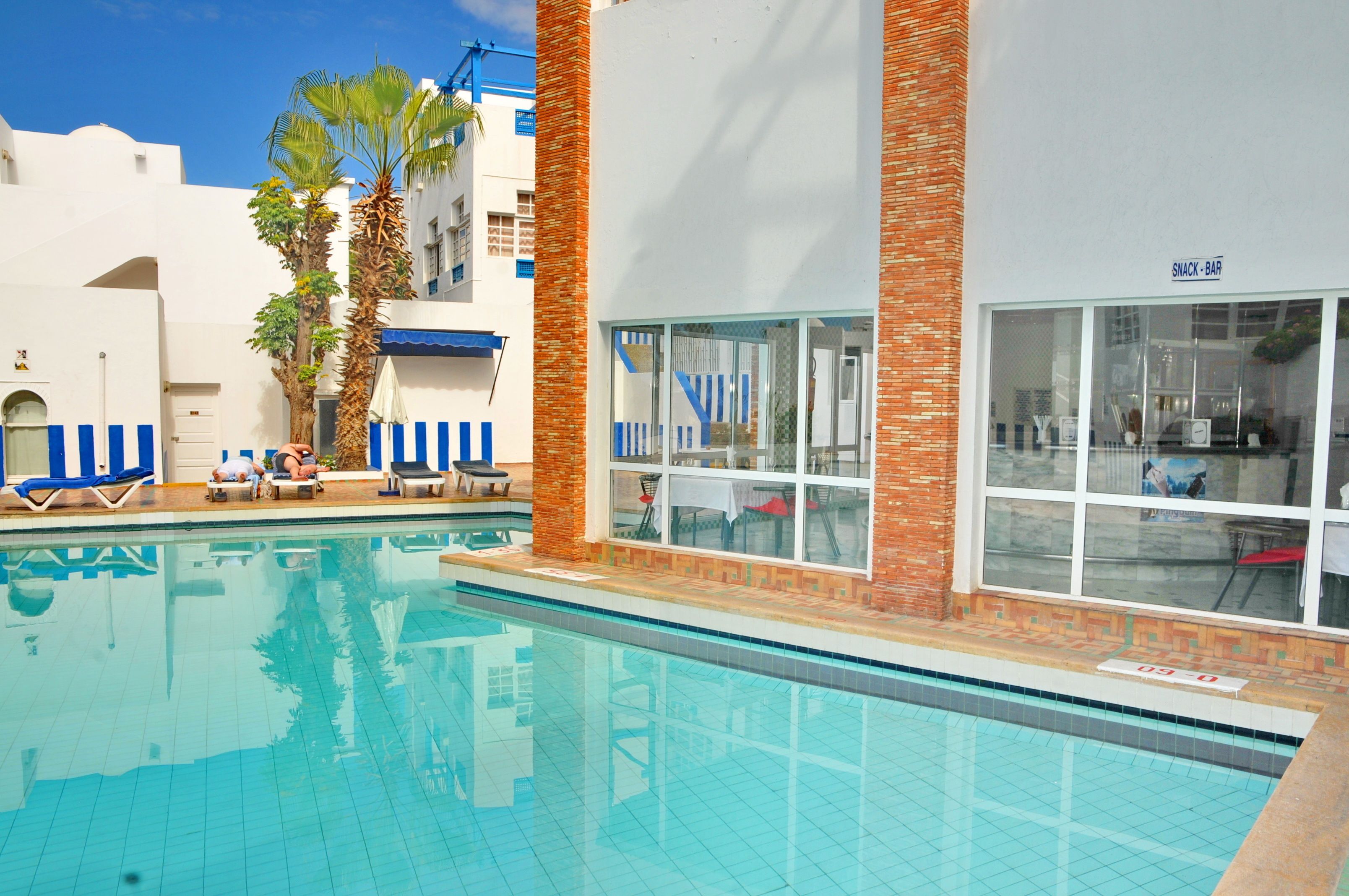 Une piscine avec des chaises longues et un bar servant des collations.