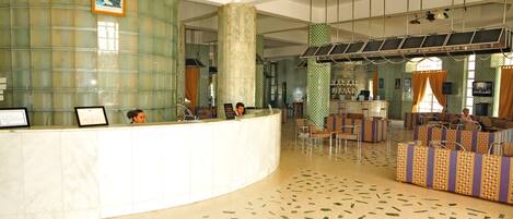 A reception area with a curved counter, seating area with patterned sofas, and a tiled floor.