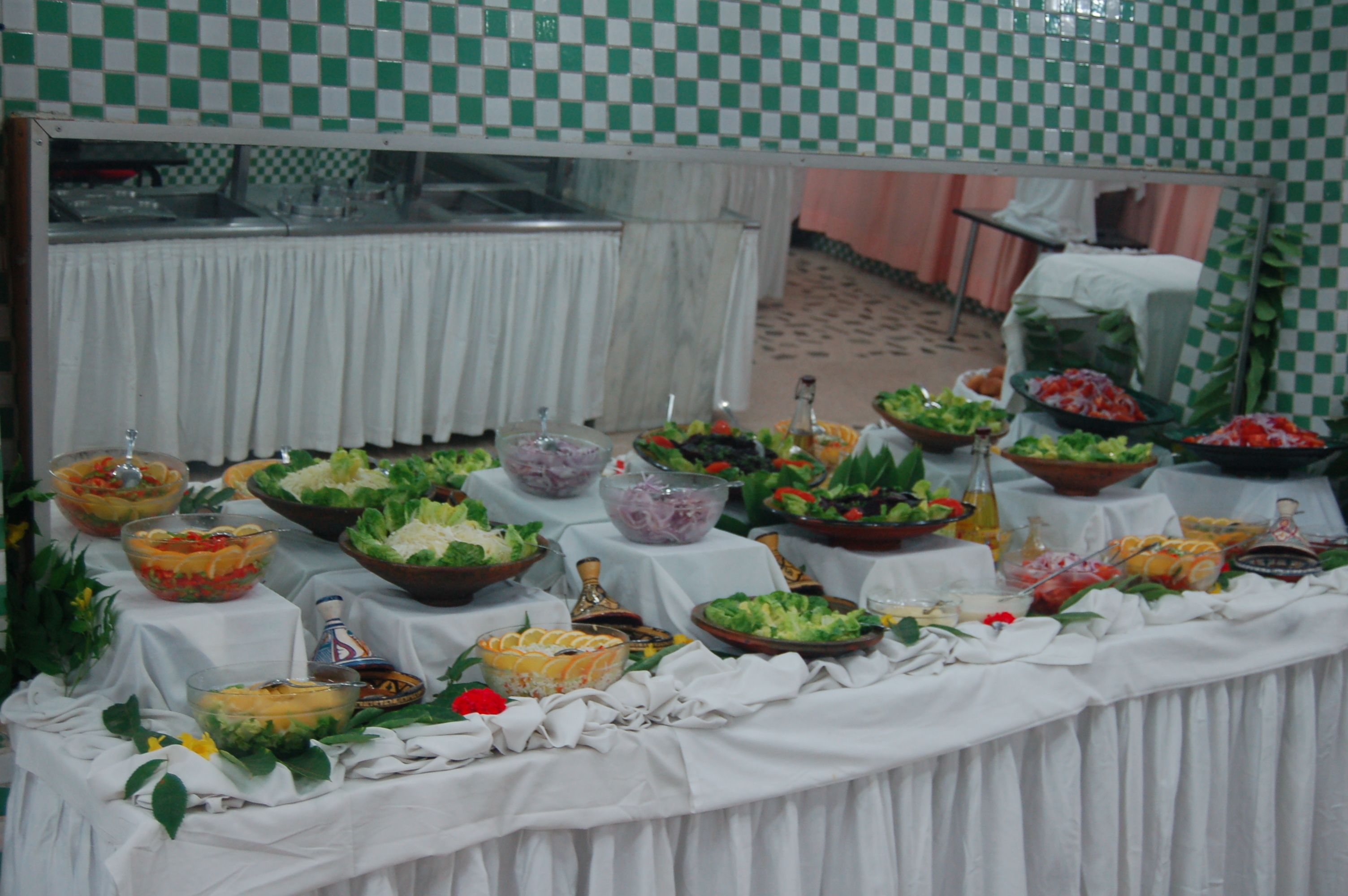 Una mesa de buffet con diversos alimentos y un espejo que refleja la sala.