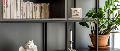 A bookshelf with books, a potted plant, and a small angel figurine.