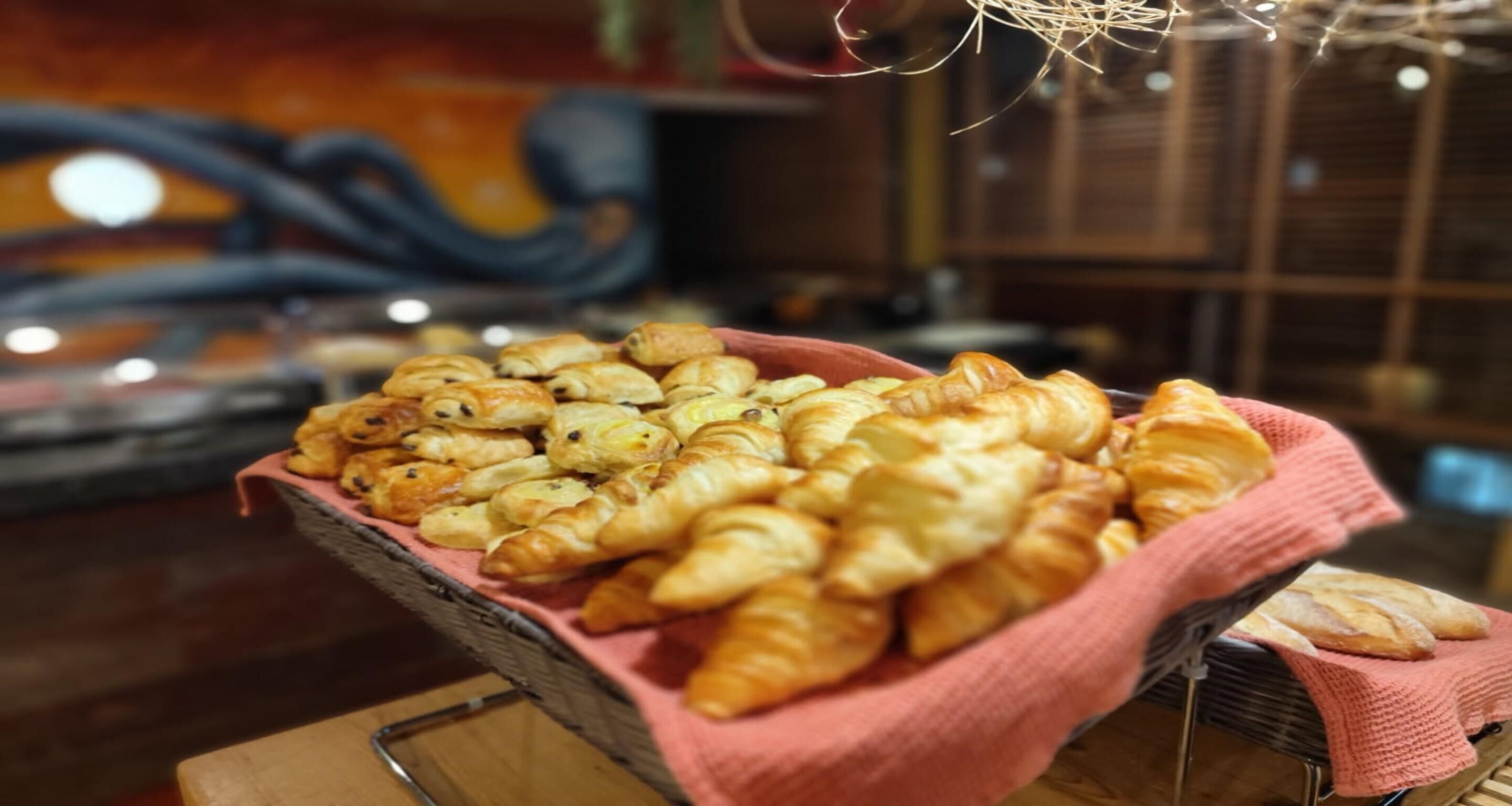 A basket of assorted pastries on a wooden table.