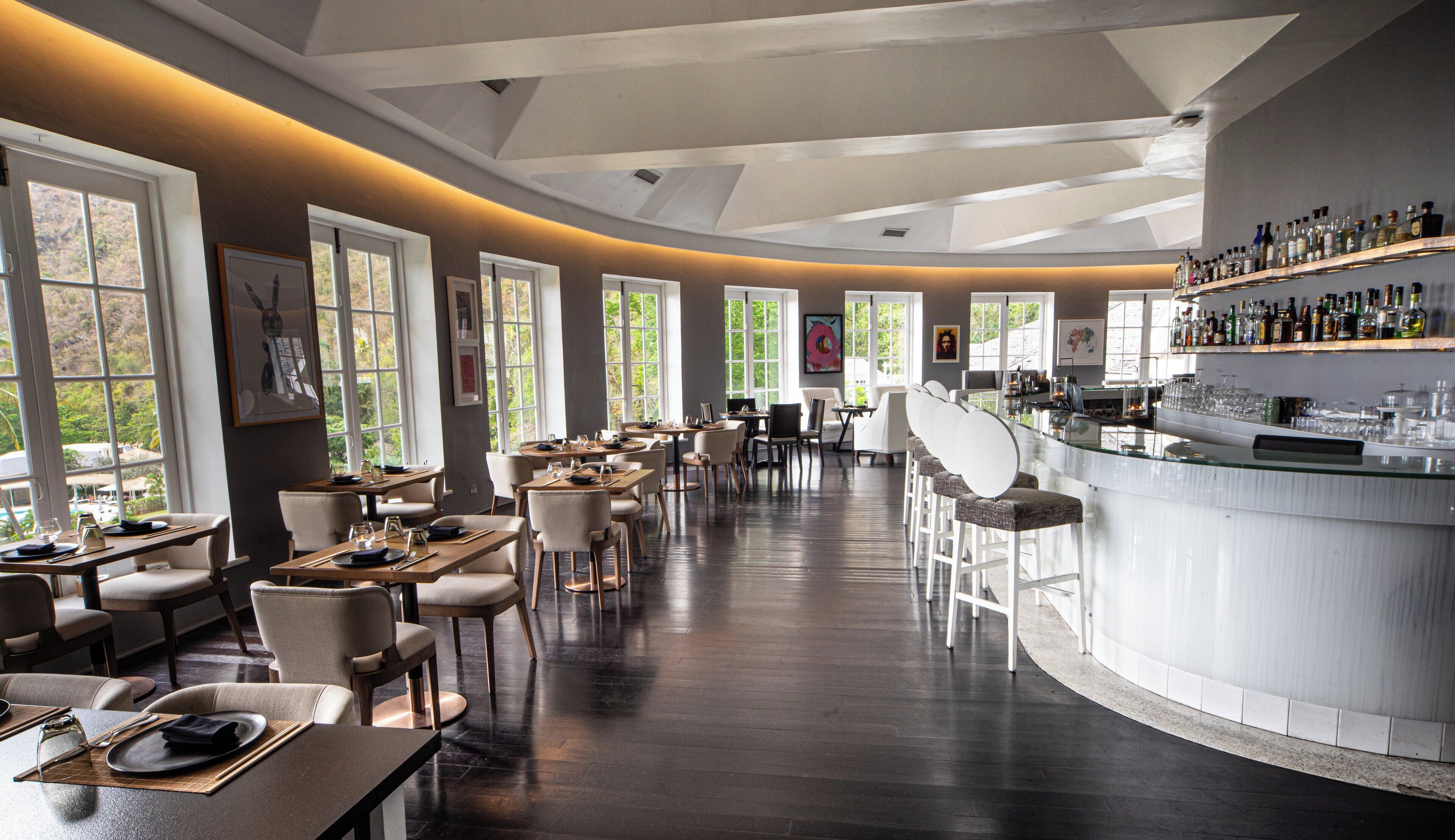 Un restaurante espacioso con techos altos, ventanas grandes y una zona de bar.