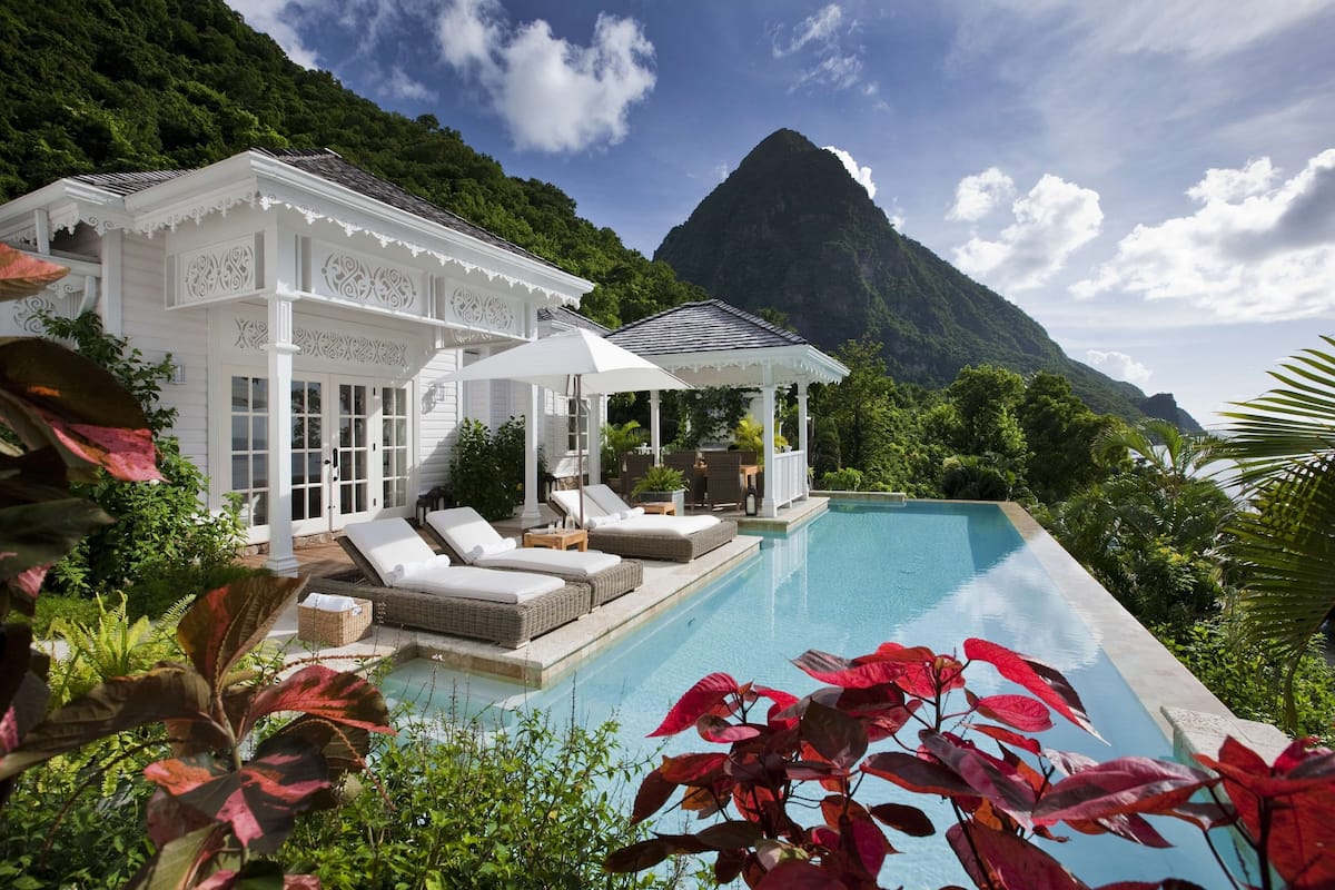 A resort with a pool, lounge area, and a mountain backdrop.