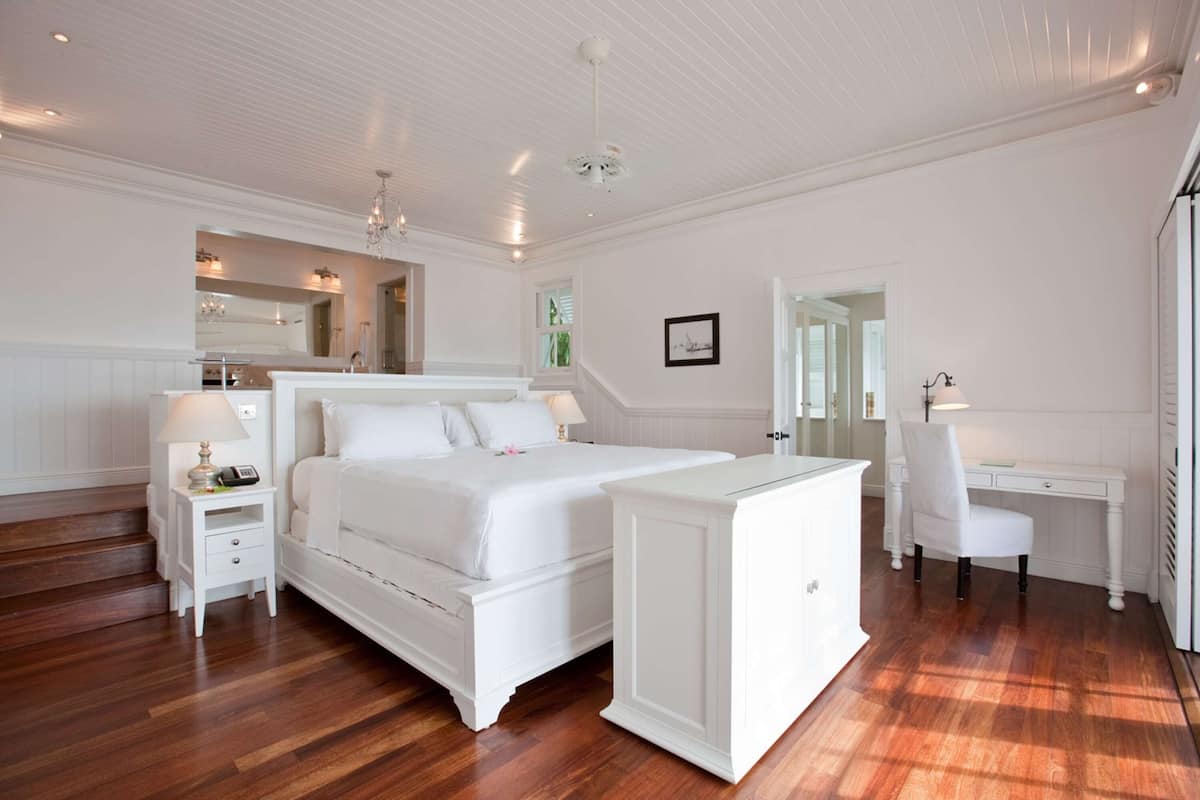 A bedroom with a large bed, bedside tables, a desk, and a chair.