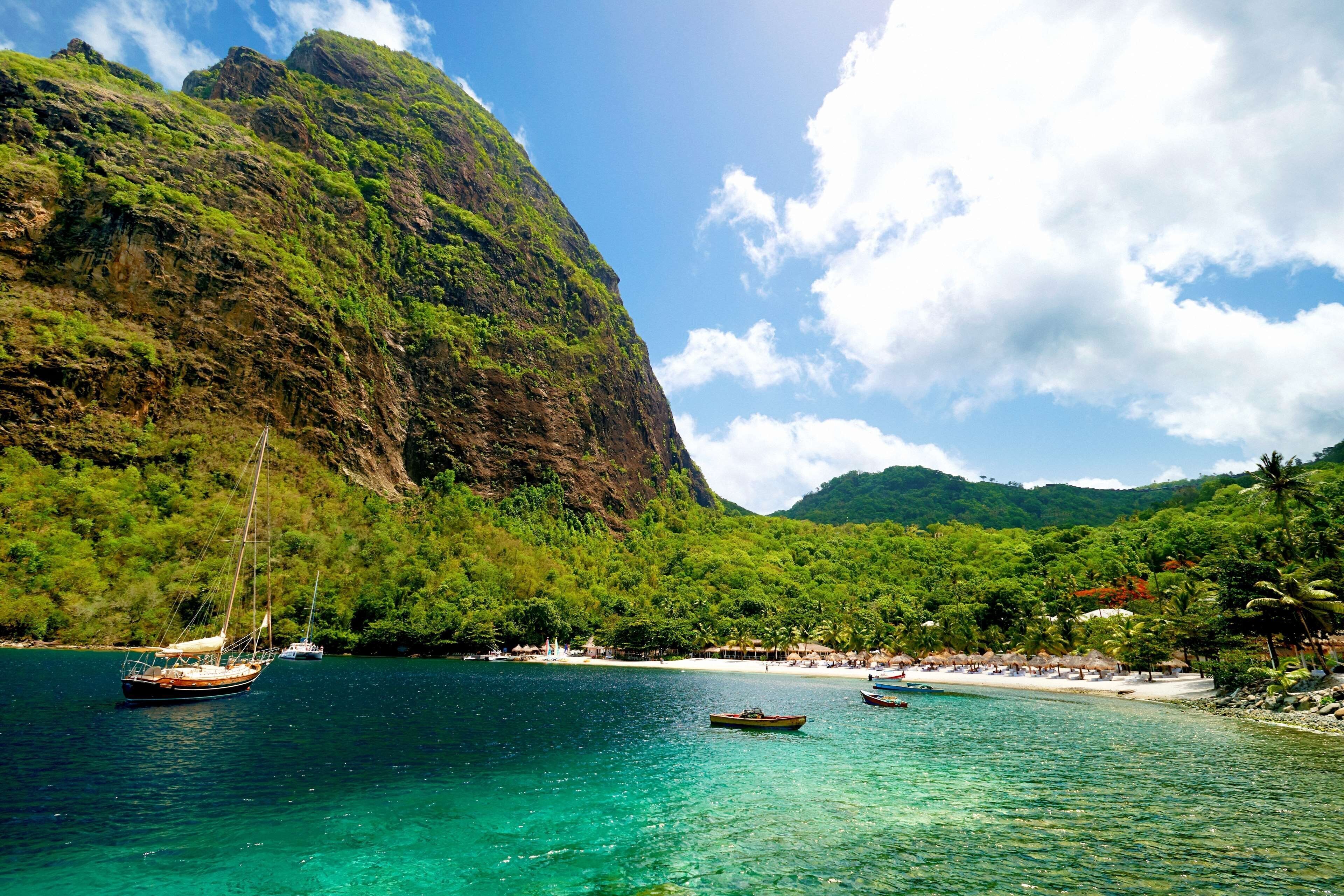 A coastal scene with boats, a beach, and a mountainous backdrop.