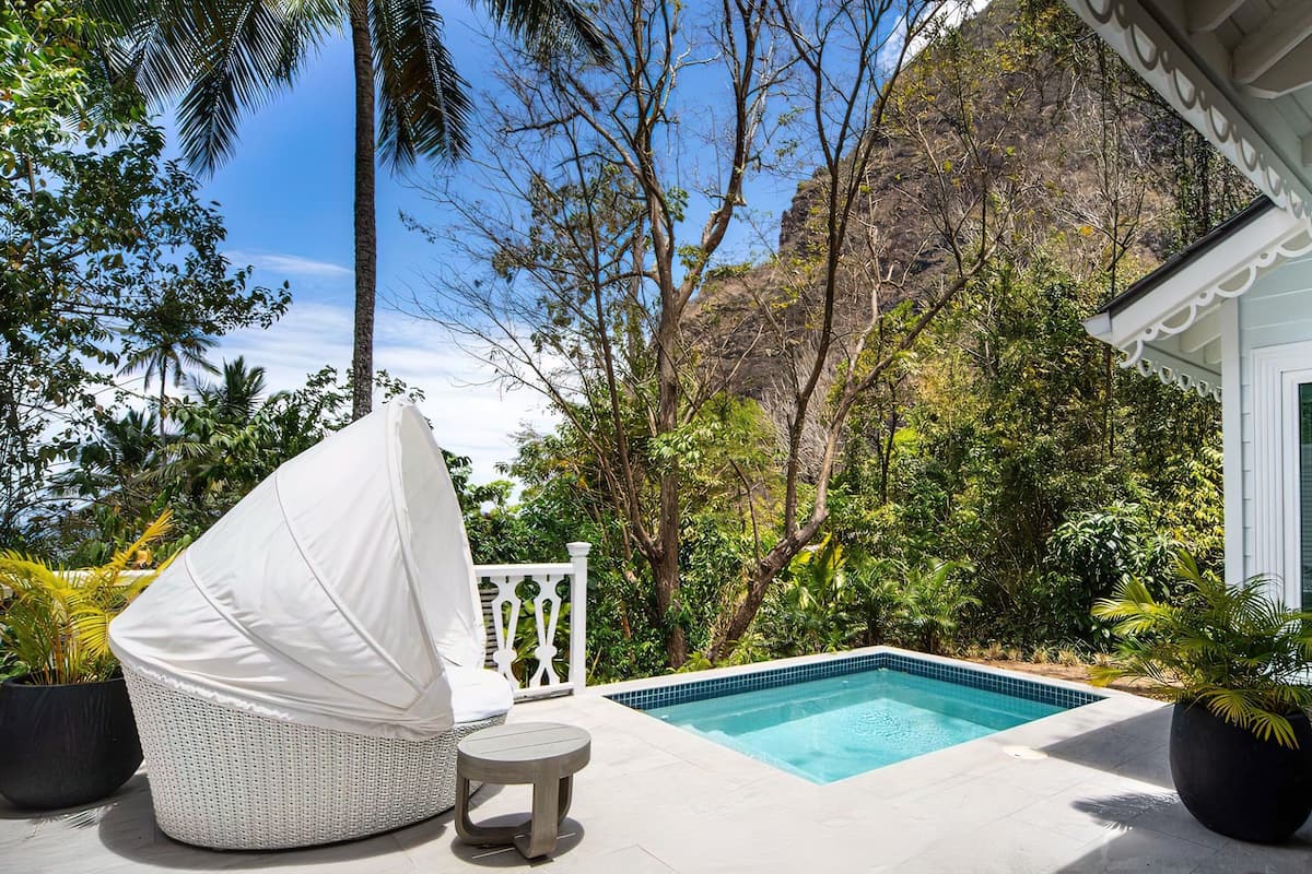 A pool area with a white umbrella, a wicker chair, and a small table.