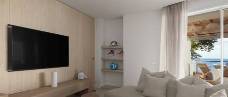 Una sala de estar moderna con un televisor de pantalla plana grande, un sofá y una mesa de centro.