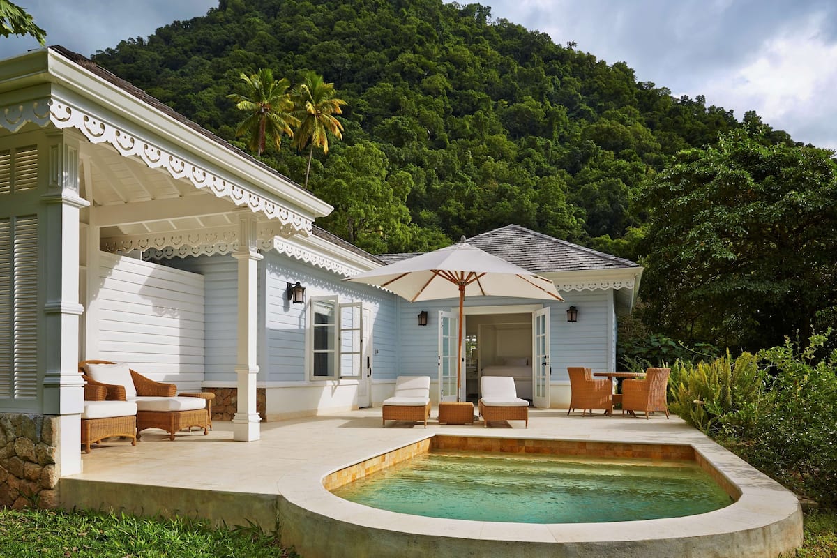 A house with a pool, white exterior, and a covered patio with wicker furniture.
