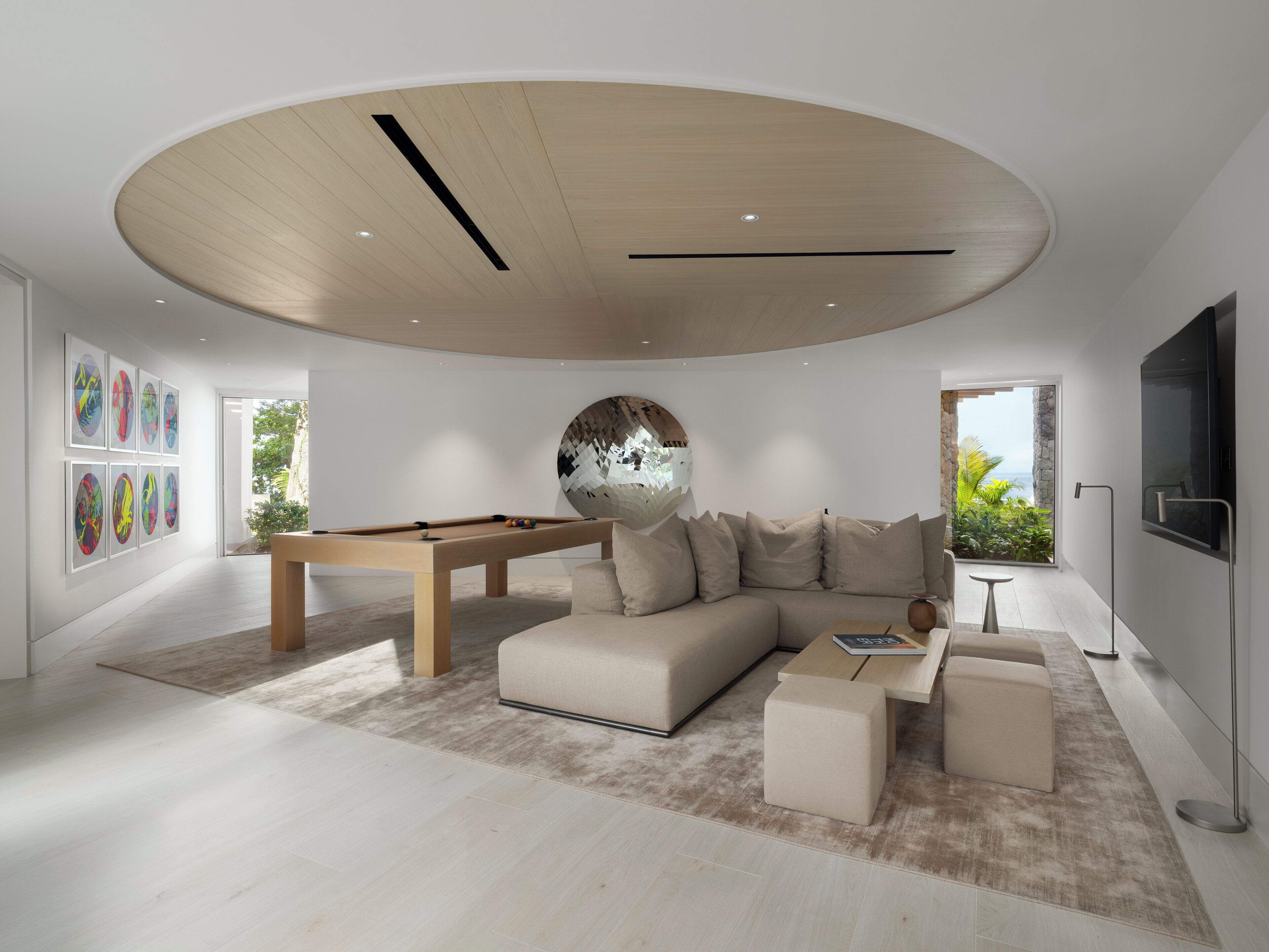 Una sala de estar moderna con mesa de billar, un sofá grande y una televisión.