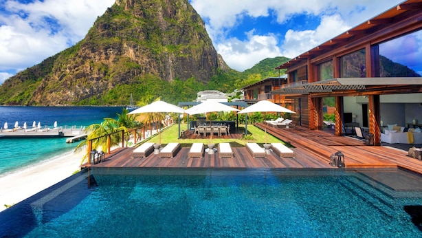 A resort with a pool, lounge chairs, umbrellas, and a mountain view. - Sugar Beach, A Viceroy Resort (Soufrière)