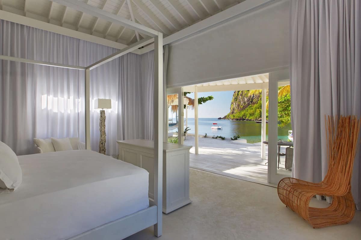 A bedroom with a four-poster bed, a nightstand, and a wicker chair.