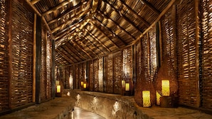 A corridor with a wooden ceiling and walls, featuring a stone pathway and wall-mounted lights. - Sugar Beach, A Viceroy Resort (Soufrière)