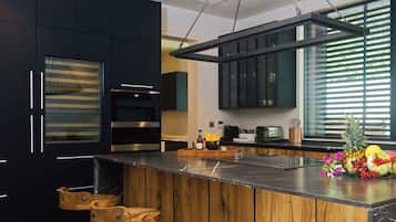 Een moderne keuken met donkere kastjes, een houten eiland en een raam met zonwering.
