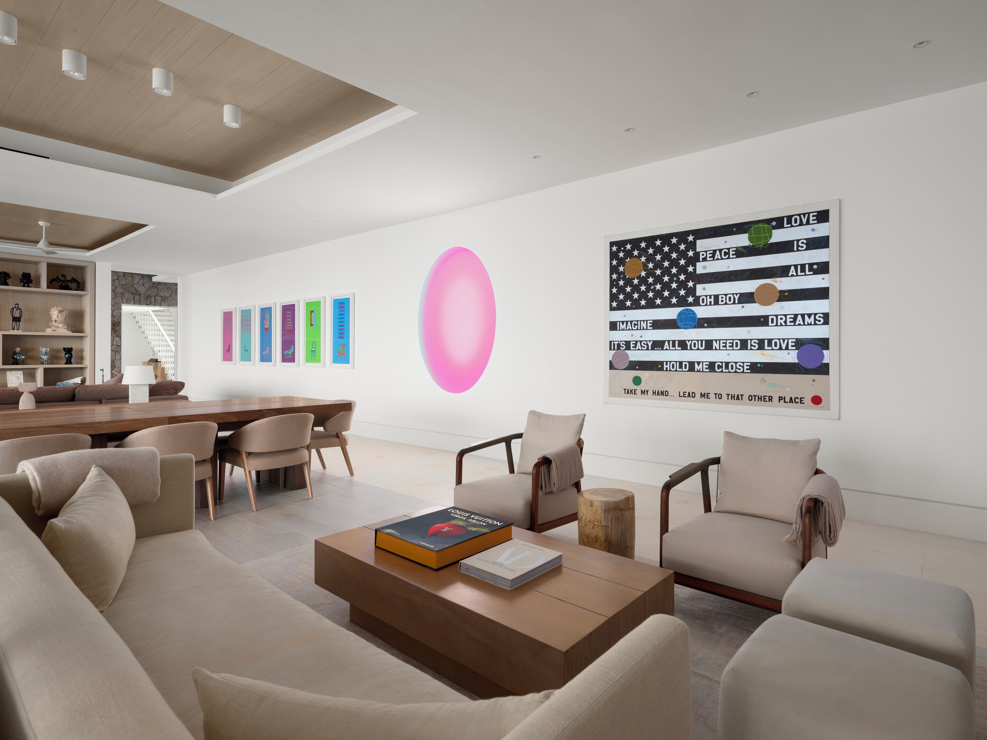 A modern living room with a wooden coffee table, beige sofas, and a bookshelf.