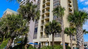 A high-rise hotel with multiple balconies, surrounded by palm trees and a well-maintained garden. - Schooner II Beach and Racquet Club (Myrtle Beach)