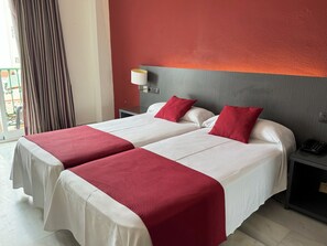 A hotel room with two beds, each with white bedding and red accents, a grey headboard, a bedside table with a lamp, and a view of a balcony. - Nerja Club by Dorobe (Nerja)