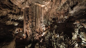 Een grot met stalactieten en -stalagmieten, verlicht met kunstlicht.
