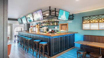A bar area with a long counter, multiple stools, and a seating bench.