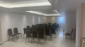 Een congreszaal met rijen stoelen, een whiteboard en een groot raam met uitzicht.