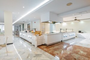 Un moderno vestíbulo de hotel con suelo de mármol, una recepción y una zona de buffet.