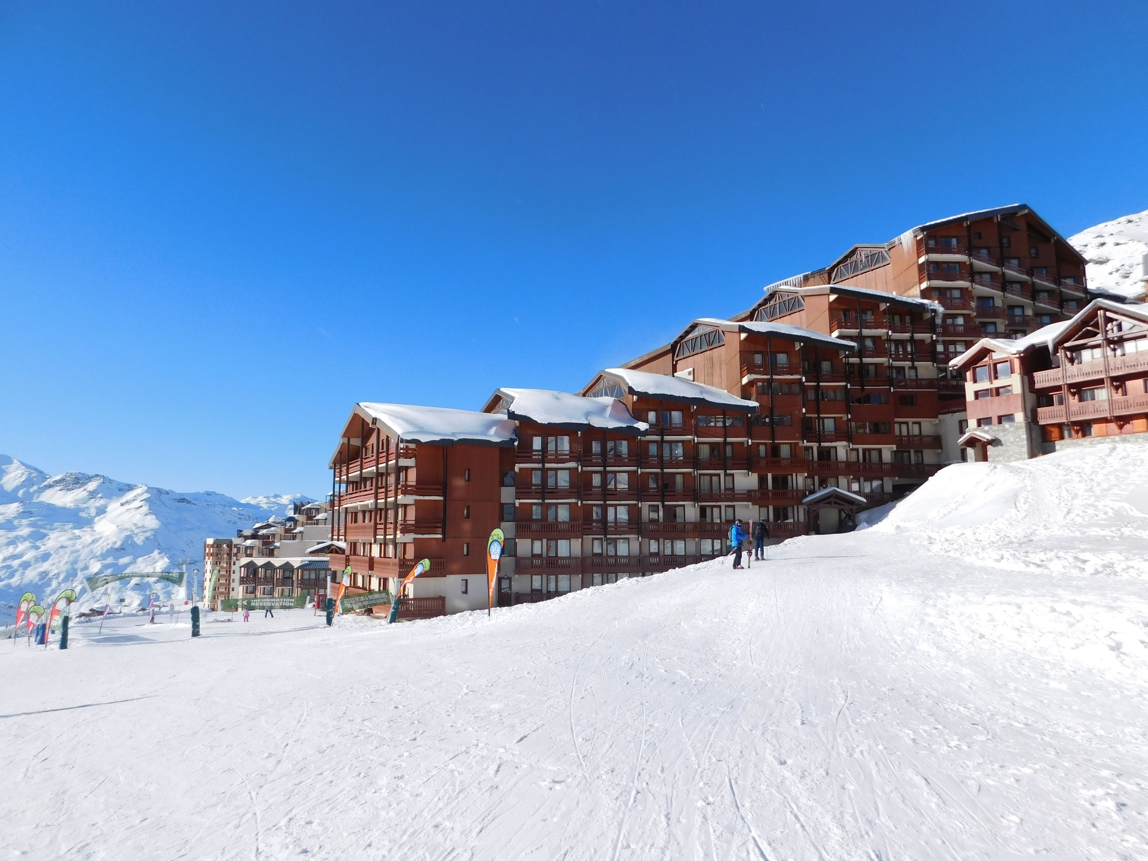 Un hôtel à plusieurs étages avec une piste de ski au premier plan.
