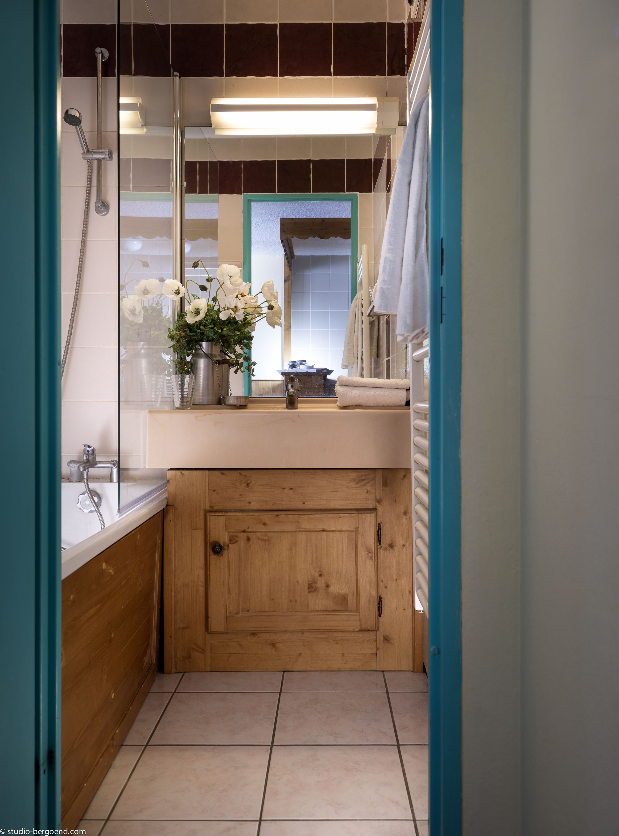 A bathroom with a wooden vanity, a shower, and a mirror.