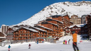 A ski resort with wooden lodges, a ski slope, and a mountain backdrop. - Residence le Cheval Blanc (Les Belleville)