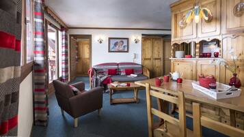 Ein gemütliches Zimmer mit einer Couch, einem Holzesstisch und einer Küchenzeile mit Holdekor.