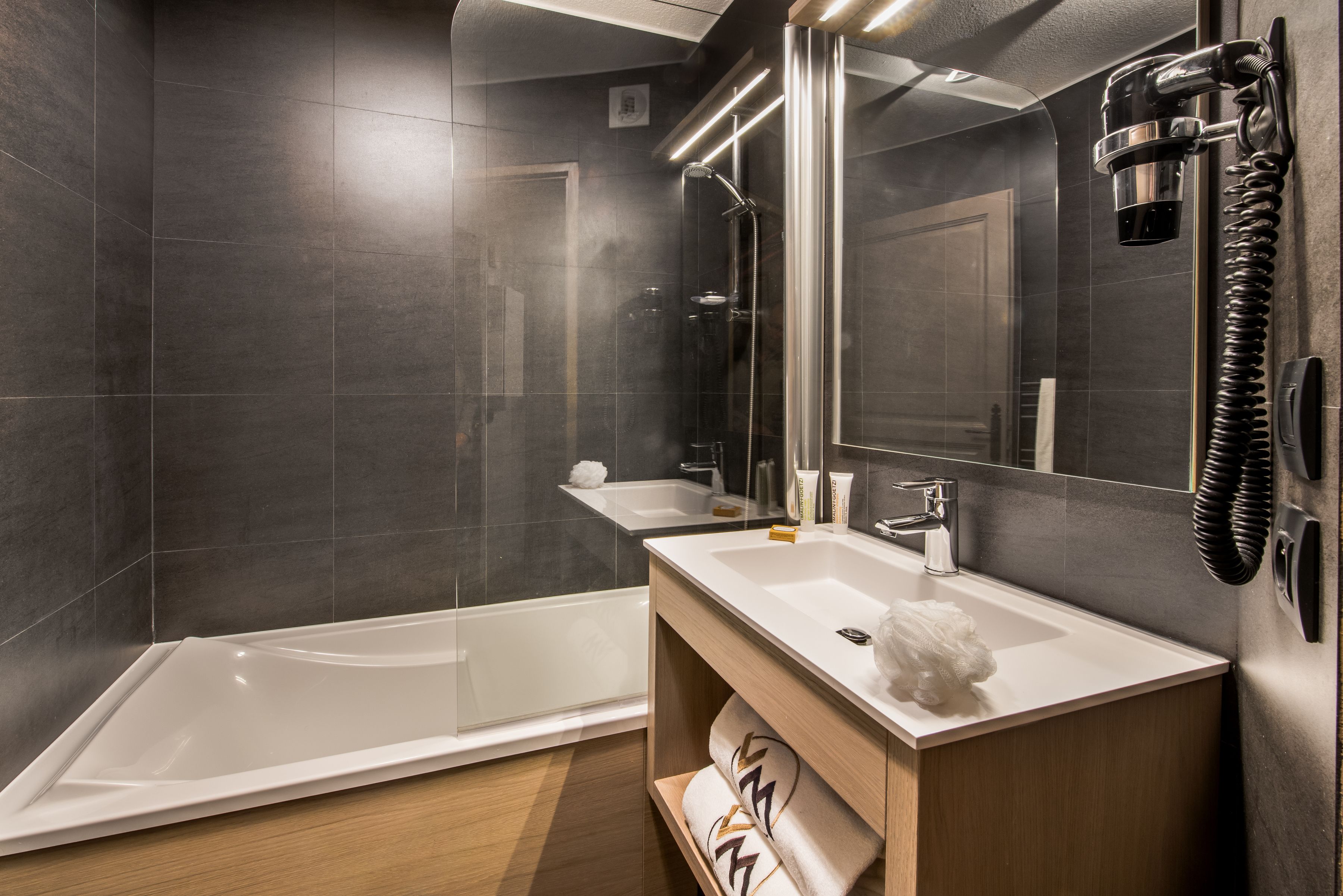 A modern bathroom with a large bathtub, a sink, and a mirror.