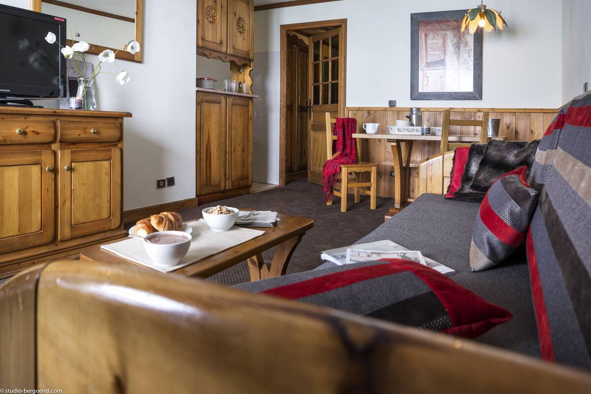 Un salon chaleureux avec un canapé en bois, une table à manger et un coin cuisine doté de meubles en bois.