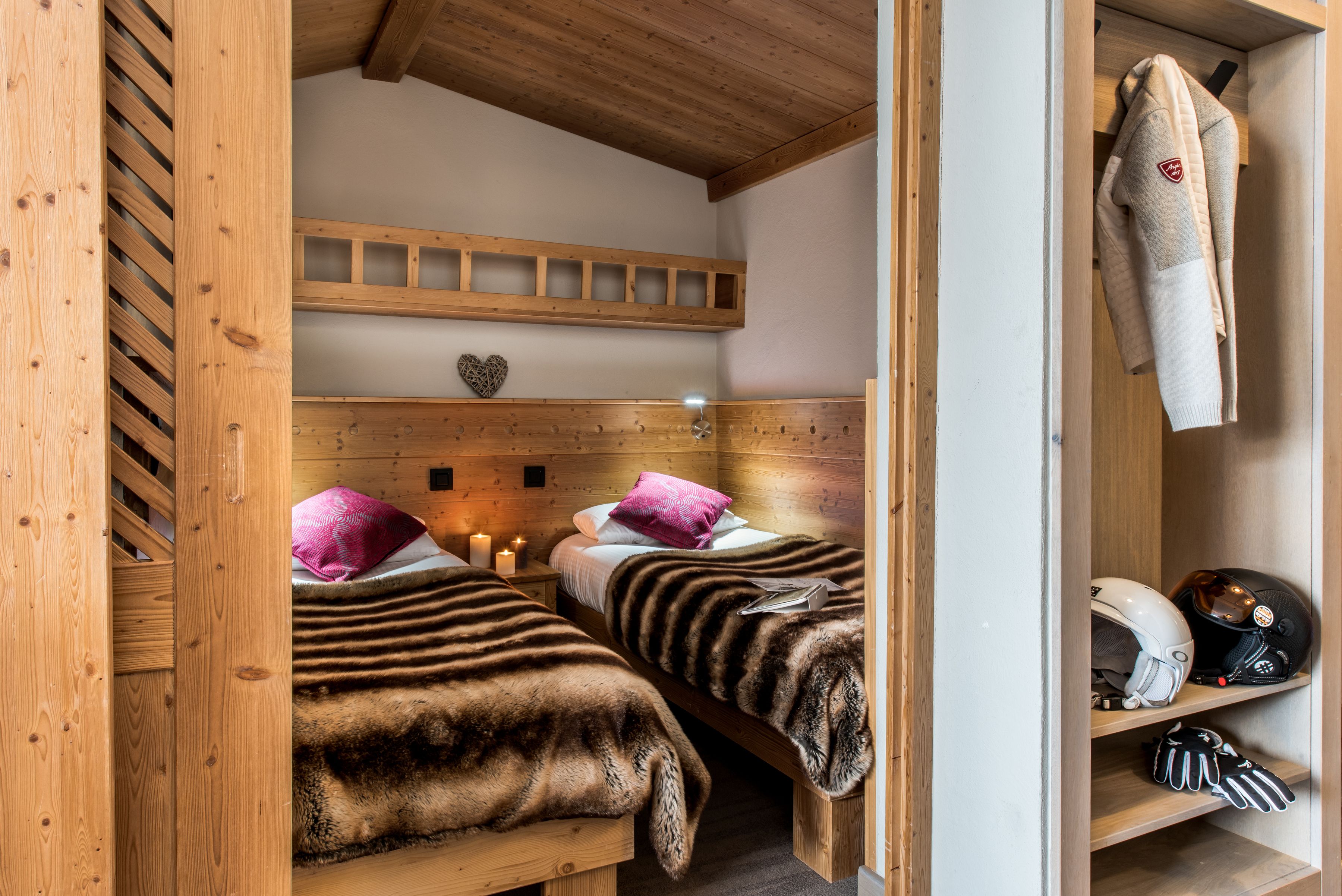 Een gezellig houten kamer met twee bedden, een plank met een helm en een hartvormige decoratie aan de muur.