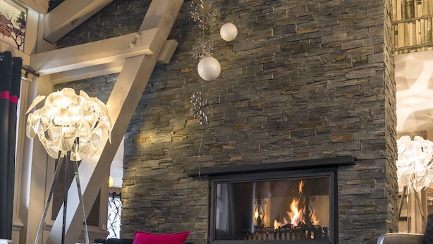A cozy interior with a stone fireplace, wooden beams, and a plush rug. - Residence Village Montana (Les Belleville)
