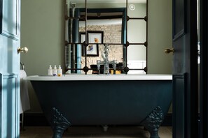 A bathroom with a freestanding bathtub, a mirror, and a sink.