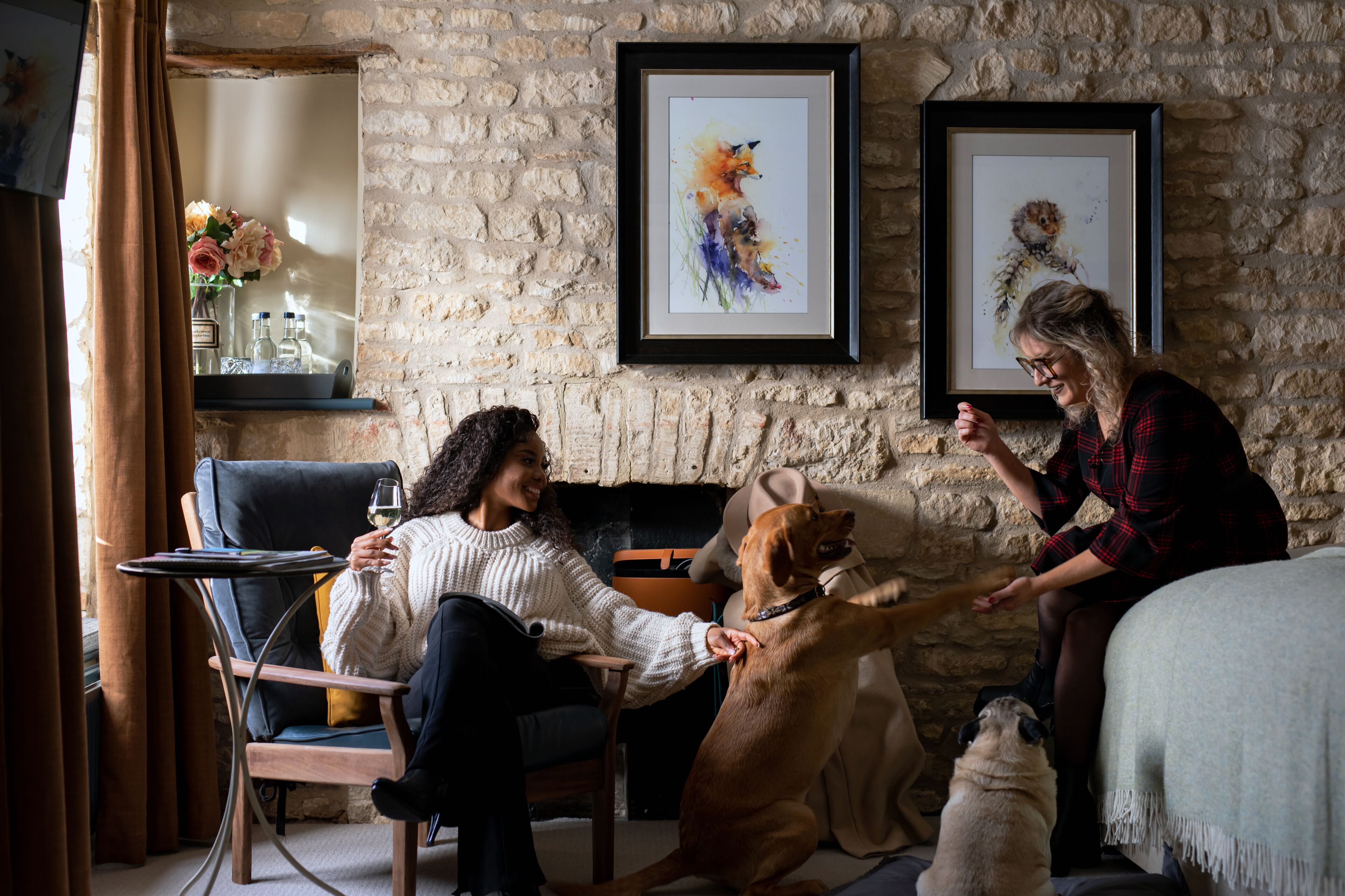 A cozy room with a stone wall, a framed artwork, and a dog interacting with a person.