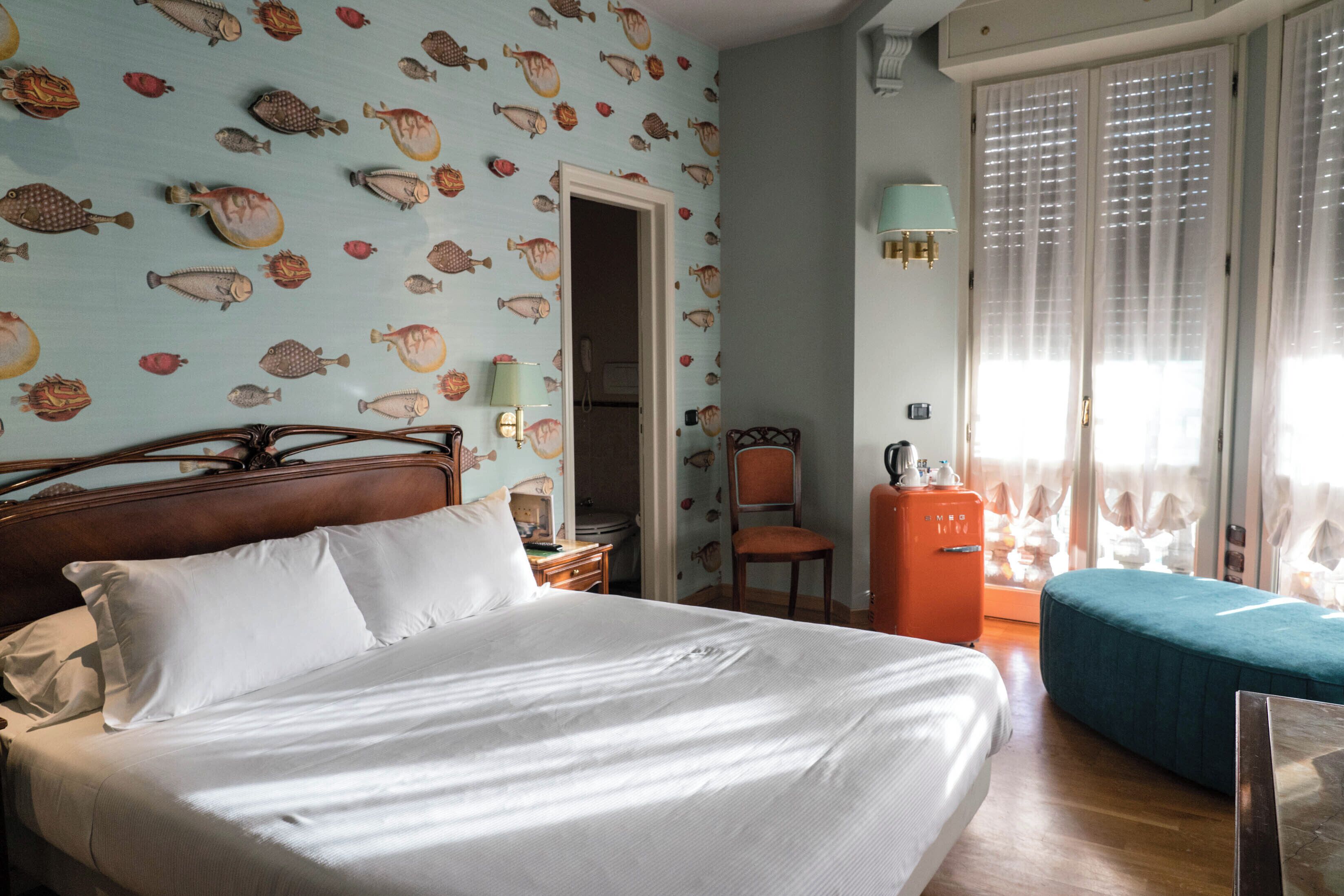 Una habitación de hotel con una cama, una silla, una mesita y un armario.