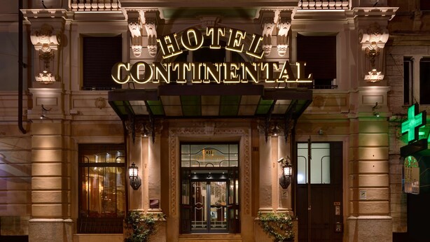 The exterior of Hotel Continental with a grand entrance, ornate columns, and a well-lit facade.